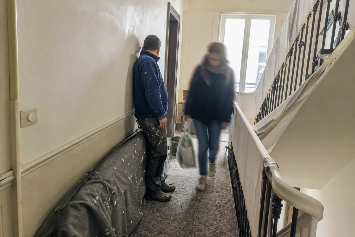 Habitante passant sur un palier en travaux de peinture, cheminement laissé libre par le peintre