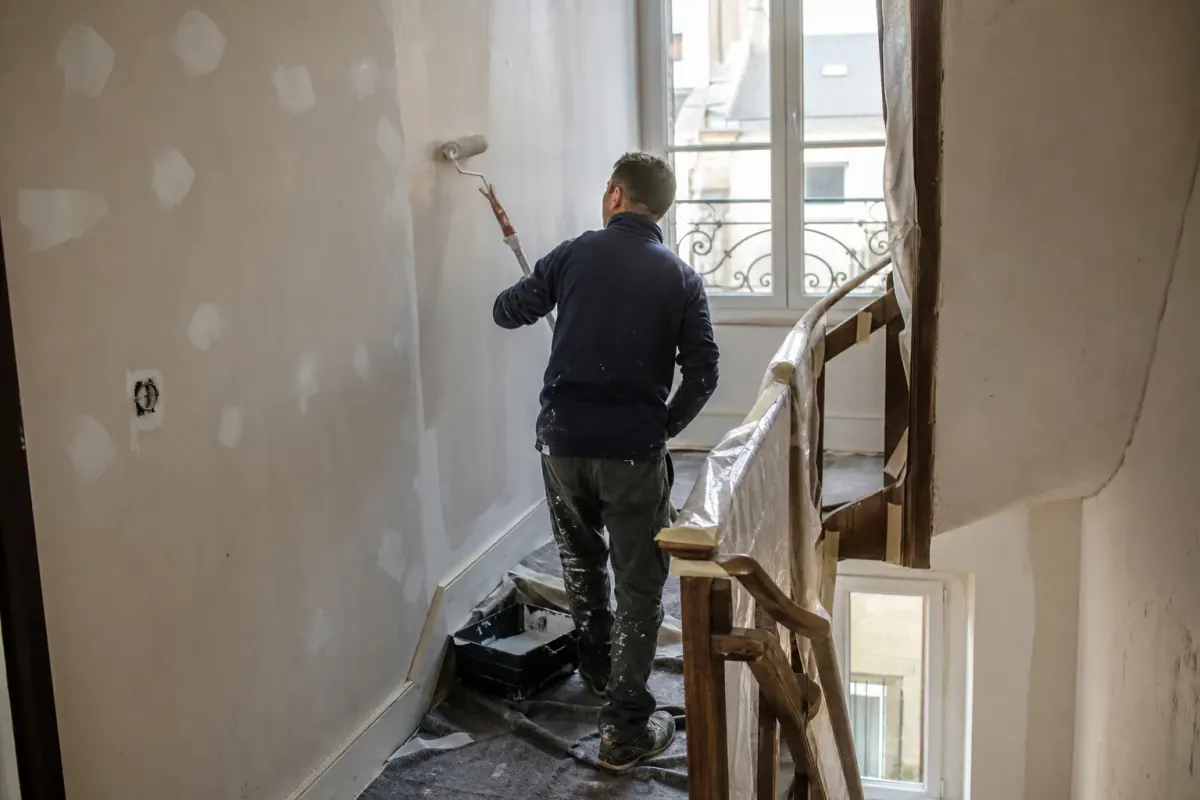Étapes de peinture d’une cage d’escalier : impression appliquée au rouleau sur mur rebouché
