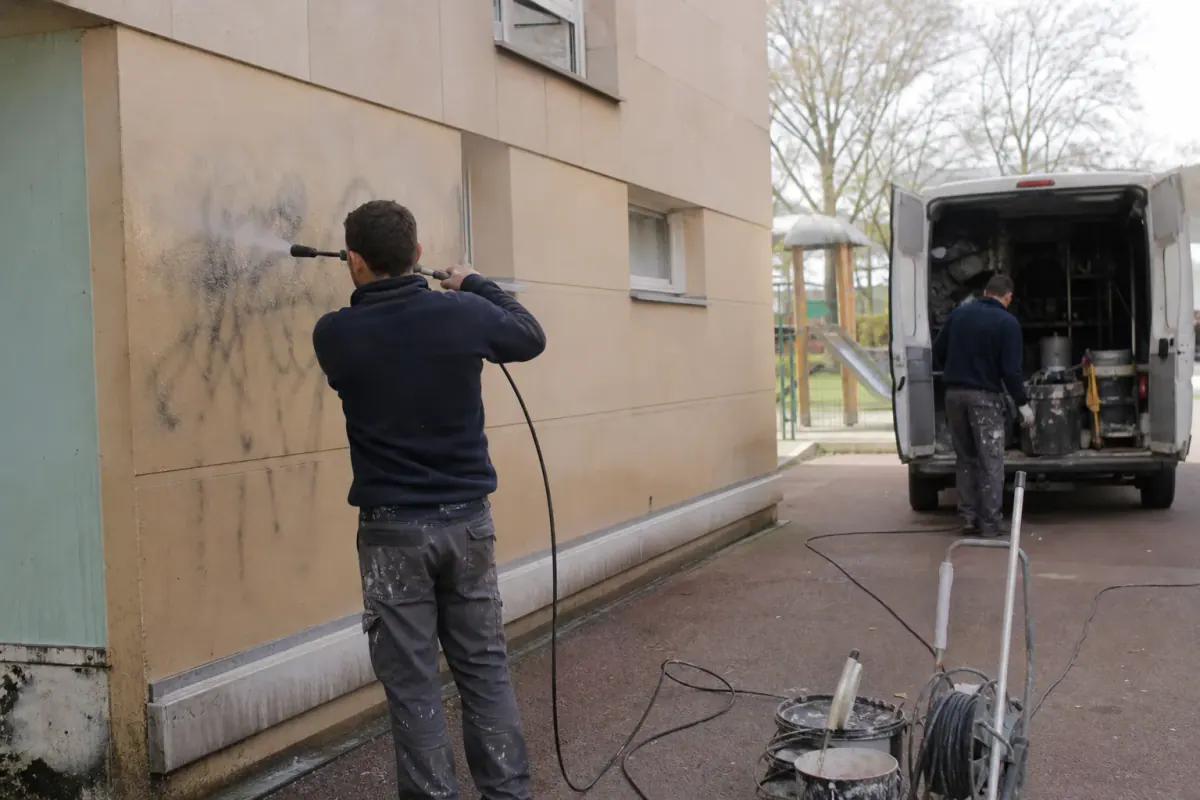 Équipe anti-graffiti intervenant sur une résidence de bailleur social, tags effacés pied d’immeuble