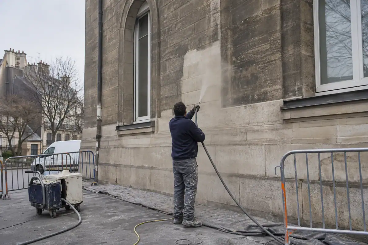 Comparaison hydrogommage et aérogommage : technicien nettoyant une façade en pierre