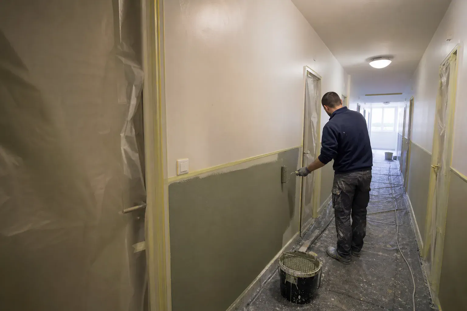 Couloir de palier d’immeuble en peinture, soubassement lessivable repris au rouleau entre les portes
