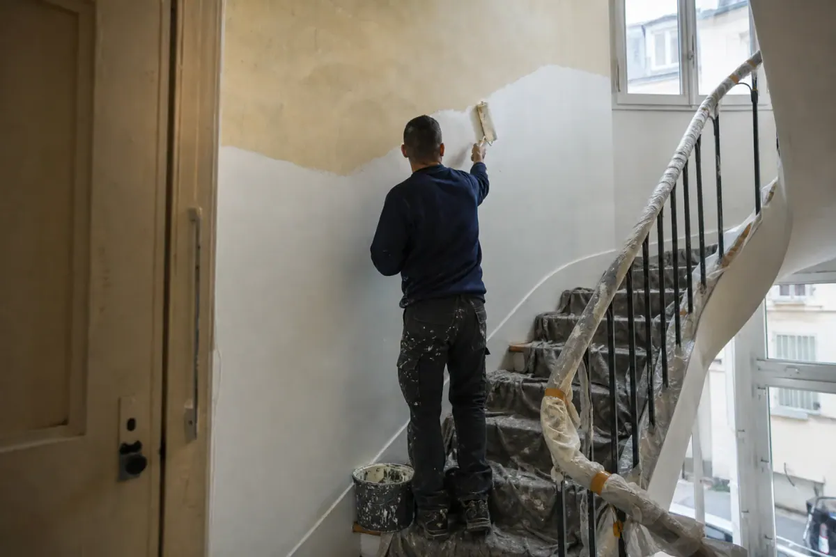 Peintre repeignant un étage de cage d’escalier, chiffrage de la peinture étage par étage