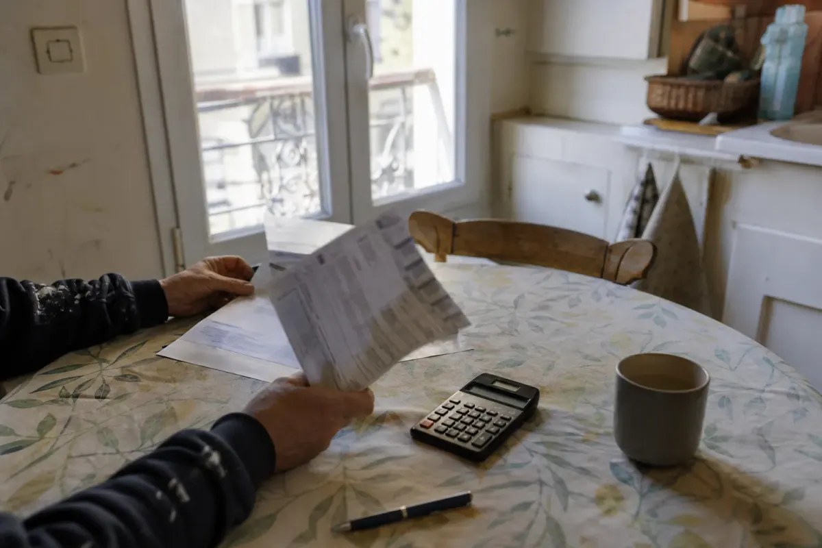 Relevé de charges de copropriété et appel de fonds posés sur une table, calculatrice à côté