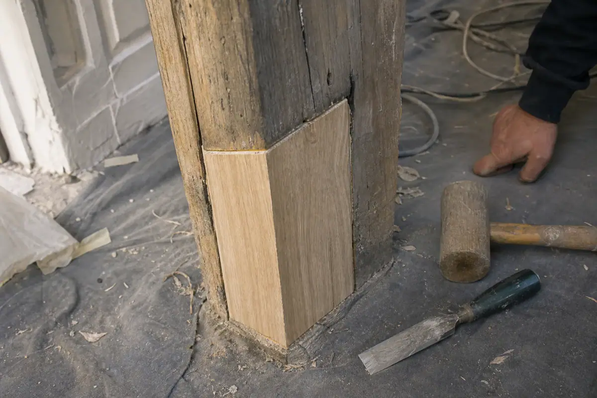 Greffe de chêne neuf encastrée au pied d’un montant de porte cochère, réparation du bois avant laquage